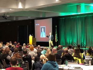 Staff member speaking on stage at a conference